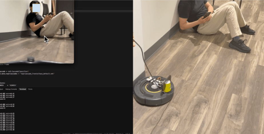A Roomba rigged with a camera and face-detection script, aimed at someone lying against a wall on their phone.